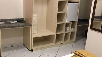 Hotelkamer met een bed, een klein bureau, een kledingkast en een koelkast.