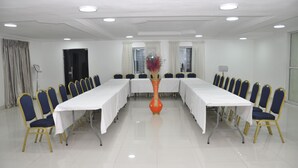 A conference room with a long table, blue chairs, and a vase of flowers. - Grand Capital Hotel (Akure)