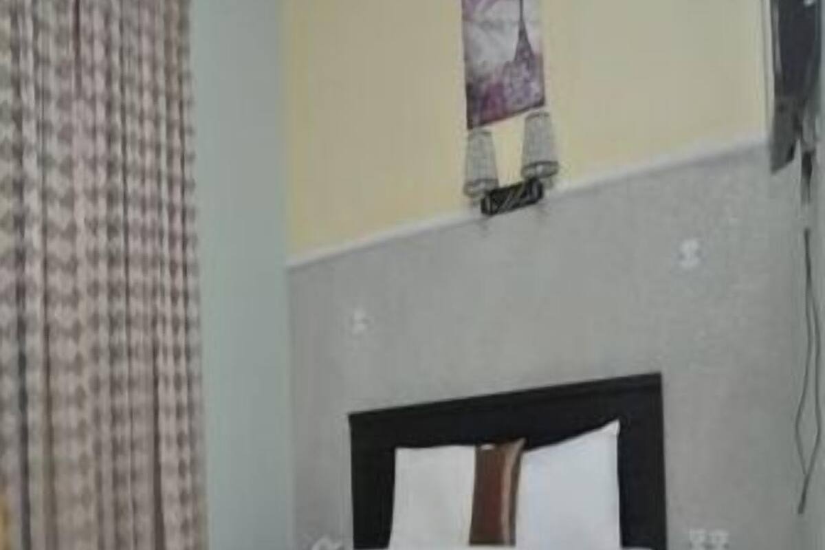 A bedroom with a bed, a nightstand, a chair, and a wall-mounted lamp.