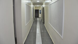 A long, narrow hallway with doors on both sides, leading to a dark room at the end. - Grand Capital Hotel (Akure)