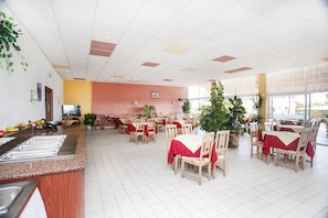 A spacious dining area with multiple tables and chairs, a buffet counter, and potted plants. - Hotel Fiesta (Varna)