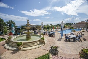 A pool area with a fountain, lounge chairs, and tables. - Hotel Fiesta (Varna)