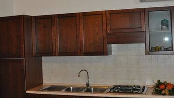 A kitchen with wooden cabinets, a sink, a stove, and a dining table with chairs.