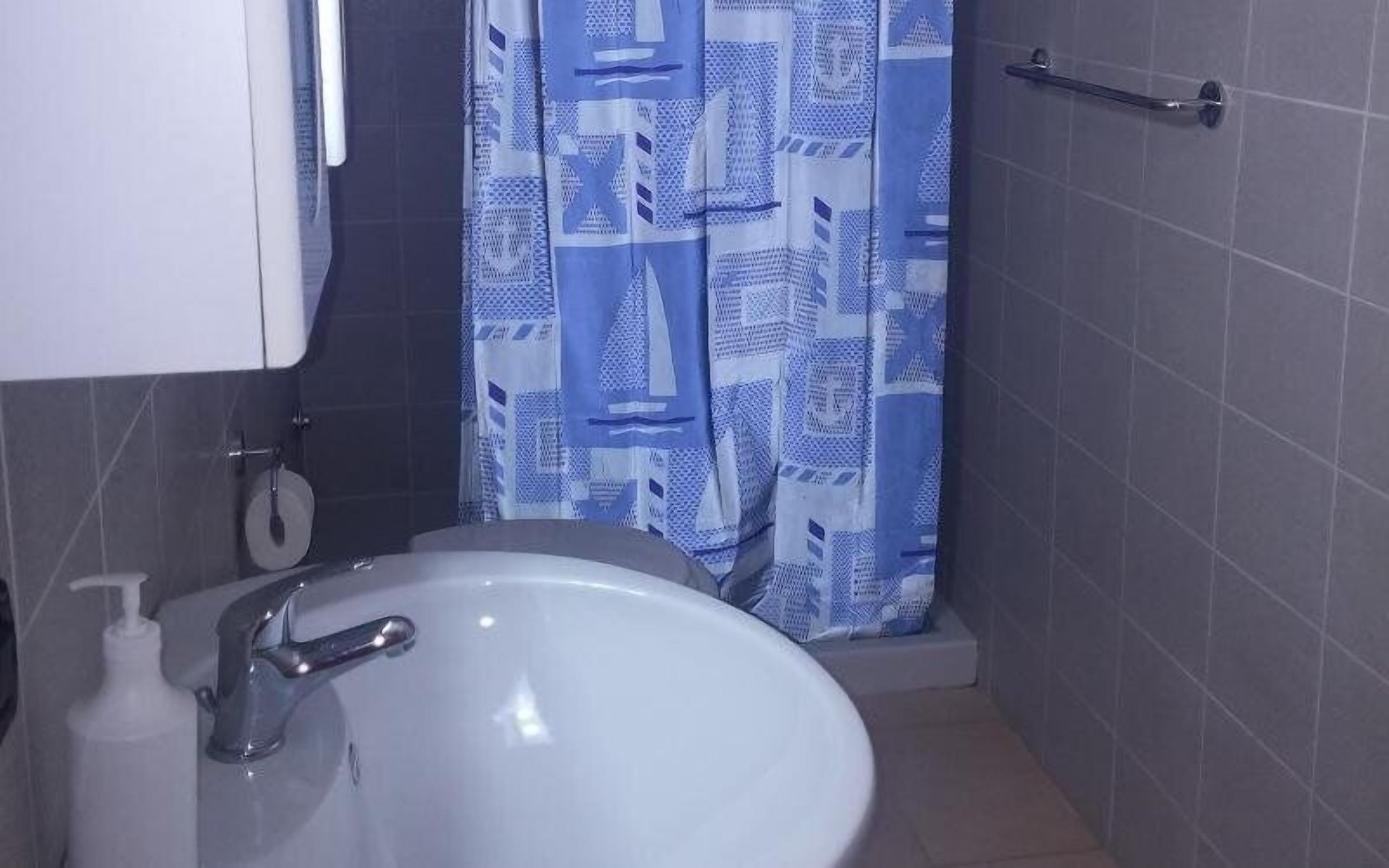 A bathroom with a white sink, a towel rack, and a shower curtain with a geometric pattern.