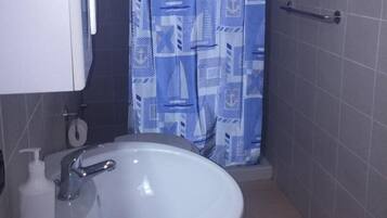 A bathroom with a white sink, a towel rack, and a shower curtain with a geometric pattern.