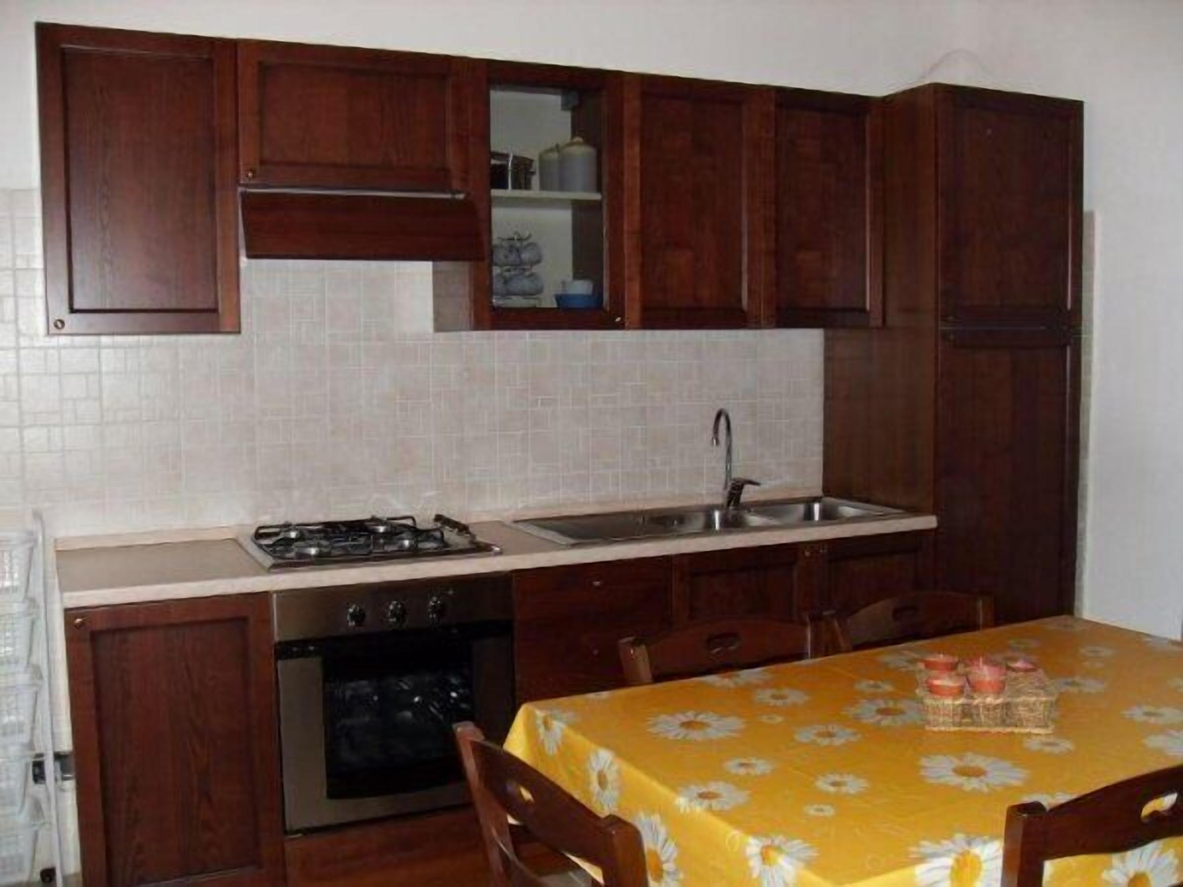 A kitchen with wooden cabinets, a gas stove, an oven, and a sink.
