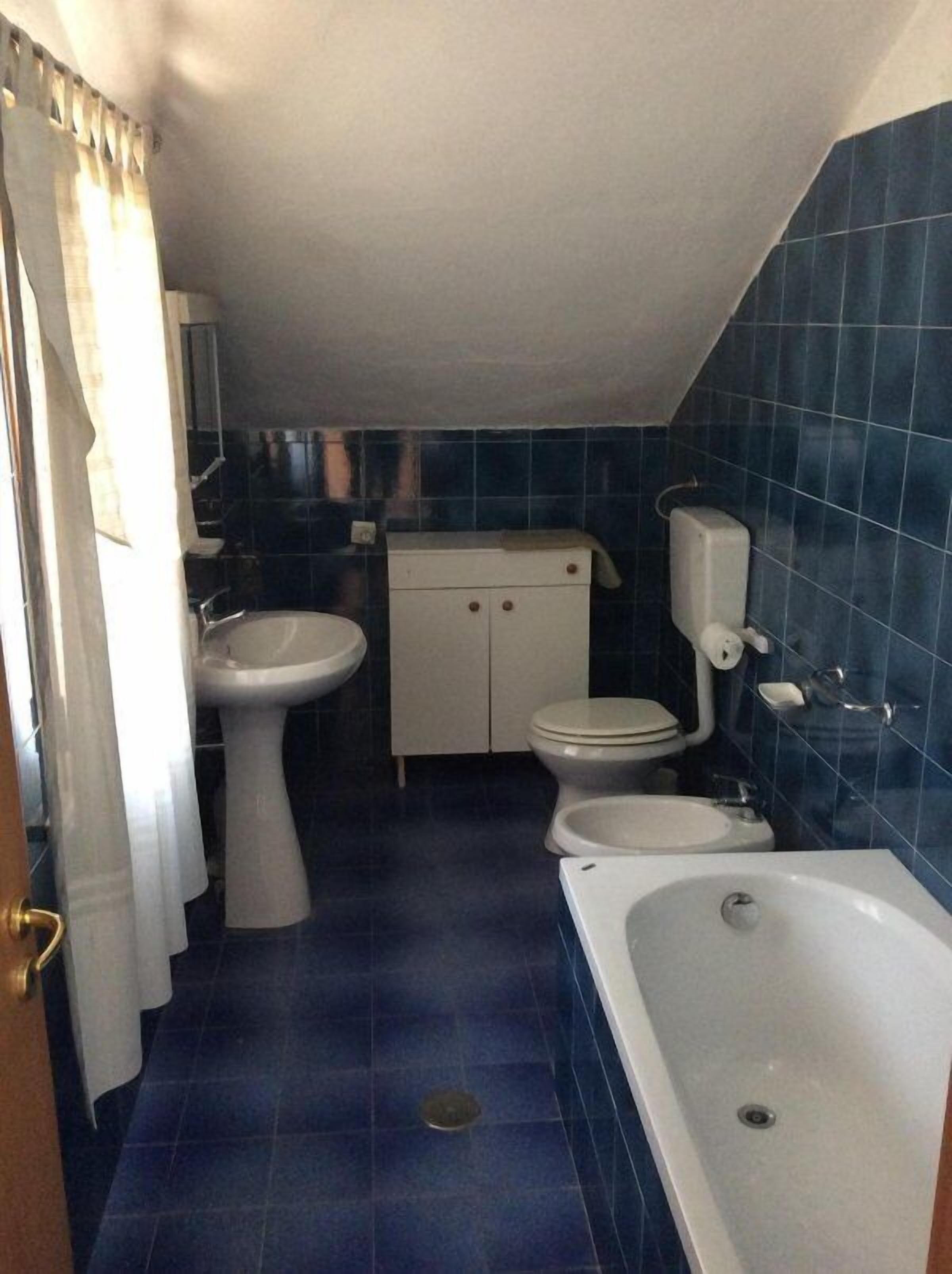 Un baño pequeño con bañera, dos lavamanos, inodoro y armario.
