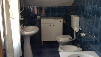 Un baño pequeño con bañera, dos lavamanos, inodoro y armario.