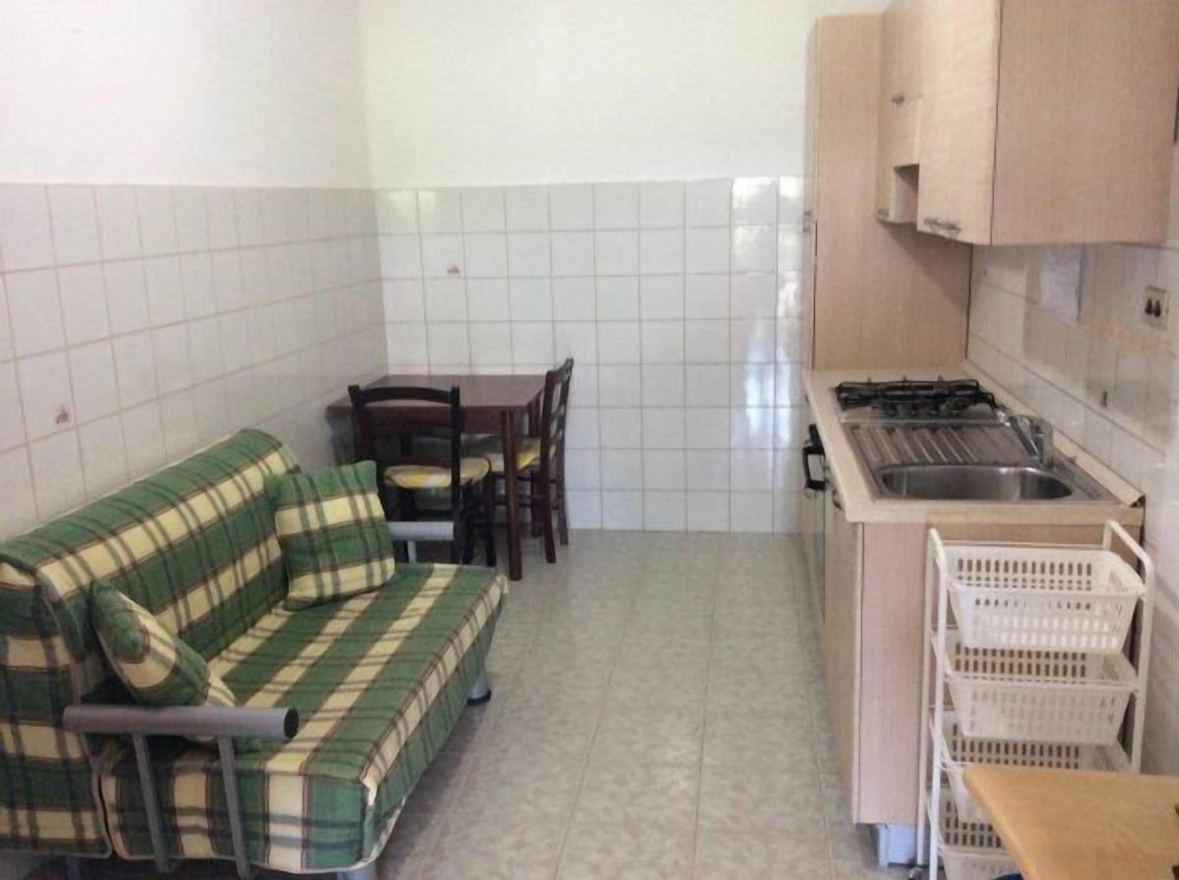 A small kitchenette with a stove, sink, and a dining area with a table and chairs.