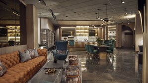 Un moderno vestíbulo de hotel con un sofá elegante, un área de descanso y un bar con estantes llenos de botellas.
