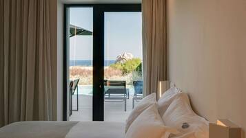 Une chambre d’hôtel avec un lit, une vue sur la plage et un balcon aménagé avec du mobilier d’extérieur.