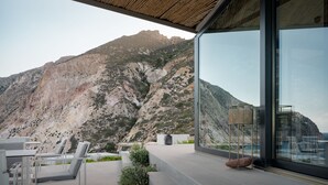 A modern outdoor seating area with tables and chairs, overlooking a mountainous landscape.