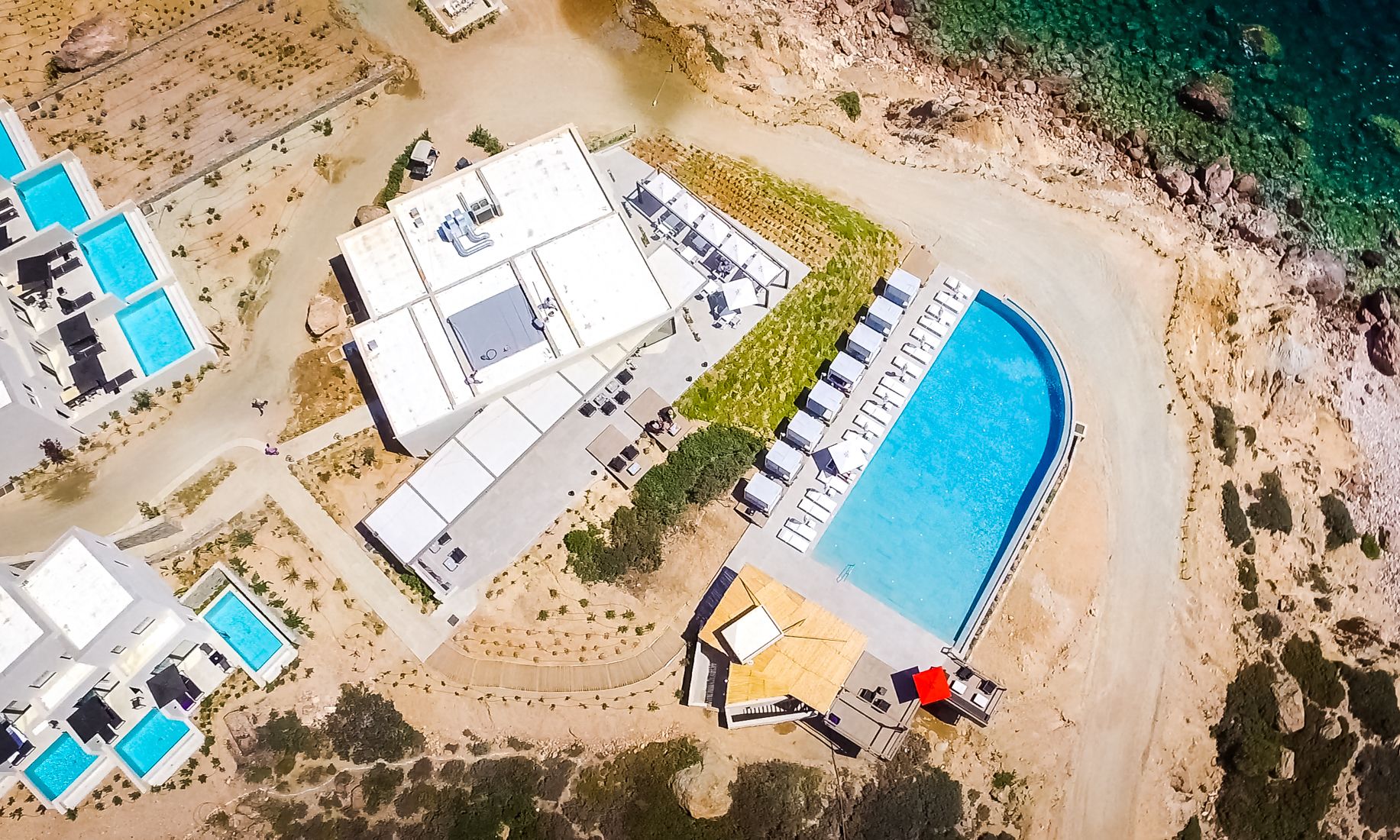 An aerial view of a resort with multiple swimming pools, a large central pool, and a beach area.