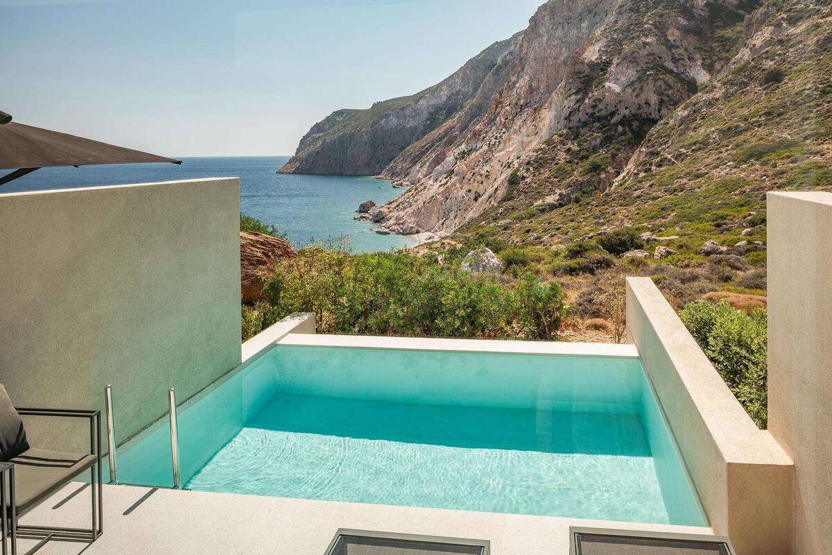 A pool with a view of the sea and rocky cliffs.