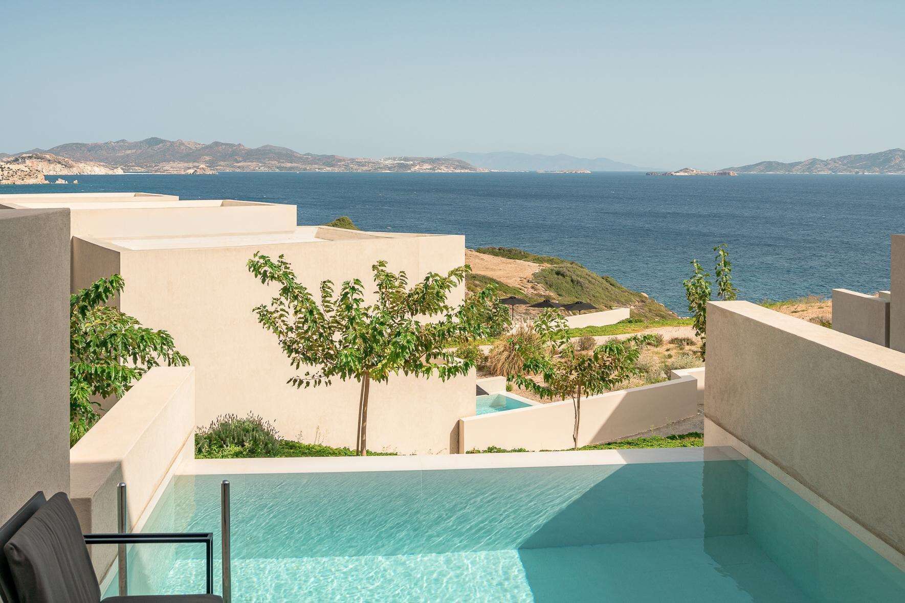 Zona de piscina con vista al mar y montañas distantes.