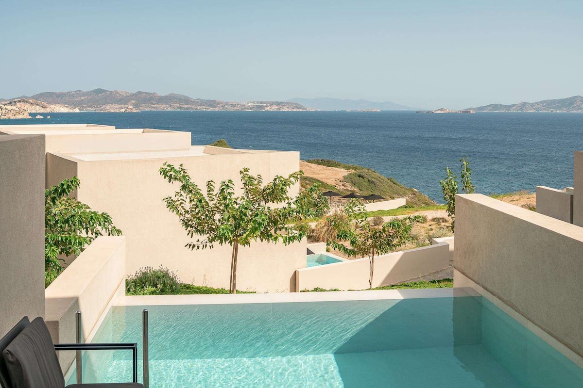A pool area with a view of the sea and distant mountains.