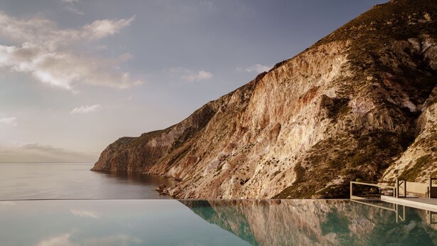 A clear view of a swimming pool with a rocky cliff in the background.
