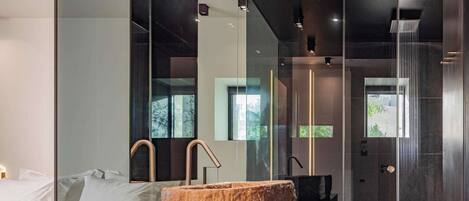 A modern bathroom with a large stone sink, glass shower enclosure, and a minimalist design.