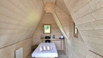 Relax in this cozy room with a massage table, sink, and natural light from a small window.