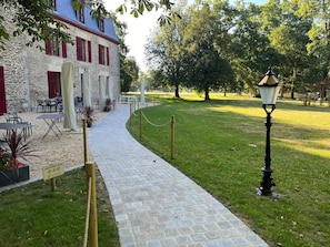 Een pad van stenen leidt naar een gebouw met terras en een lantaarnpaal.