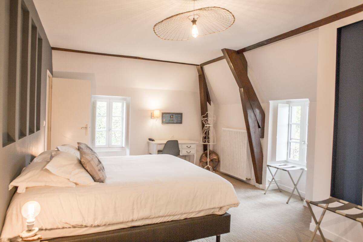 Une chambre à coucher avec un grand lit, un bureau, une chaise et un radiateur.