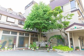 Un hotel con fachada de piedra, un gran árbol en frente y un cartel que dice 'Park Hotel'.