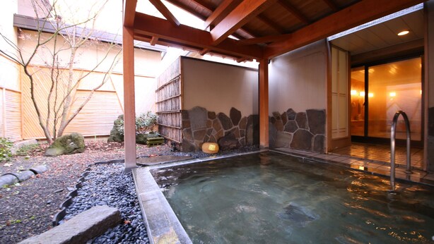 A hot spring area with a stone wall, wooden beams, and a small pool. - Kawaguchiko Park Hotel (Fujikawaguchiko)
