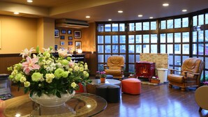 A spacious lobby with a large window, comfortable seating, and a decorative vase of flowers. - Kawaguchiko Park Hotel (Fujikawaguchiko)