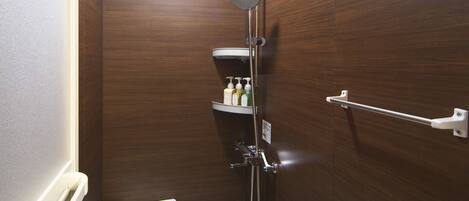 Un baño moderno y compacto con ducha, inodoro y estante de almacenamiento.
