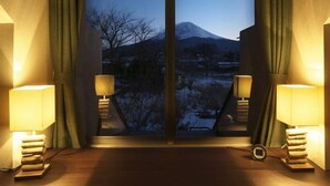A room with a large window, two bedside lamps, and a stack of books on the floor. - Kawaguchiko Park Hotel (Fujikawaguchiko)