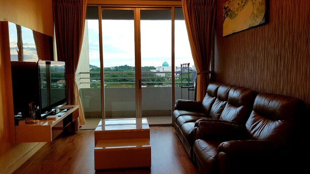 A living room with a leather sofa, a flat-screen TV, a wooden coffee table, and a balcony with a view of the city. - TnJ Home (Kota Kinabalu)