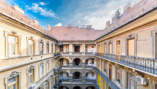 Une cour intérieure avec un espace central ouvert, entourée de bâtiments dotés de balcons et de plusieurs étages.
