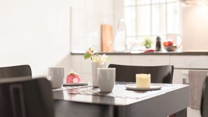 Une table à manger avec une bougie, un vase rempli de fleurs et un objet rose posé sur une assiette.