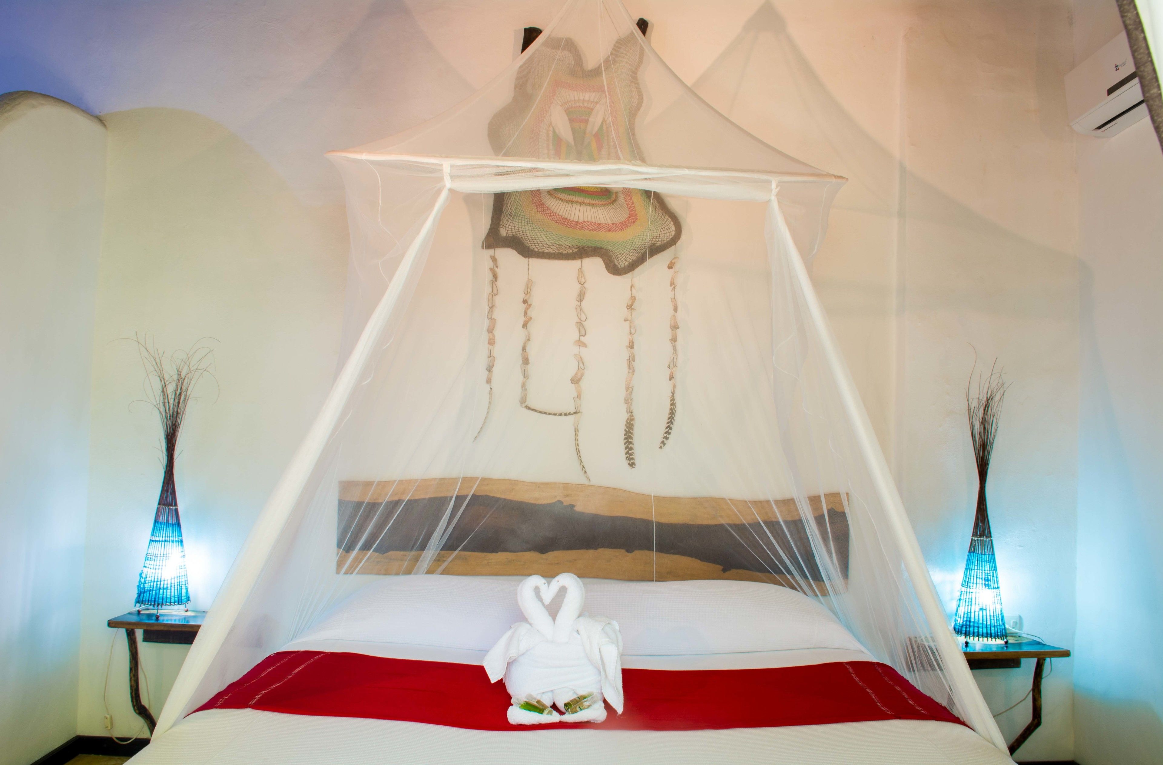 A bed with a white canopy and a heart-shaped towel.