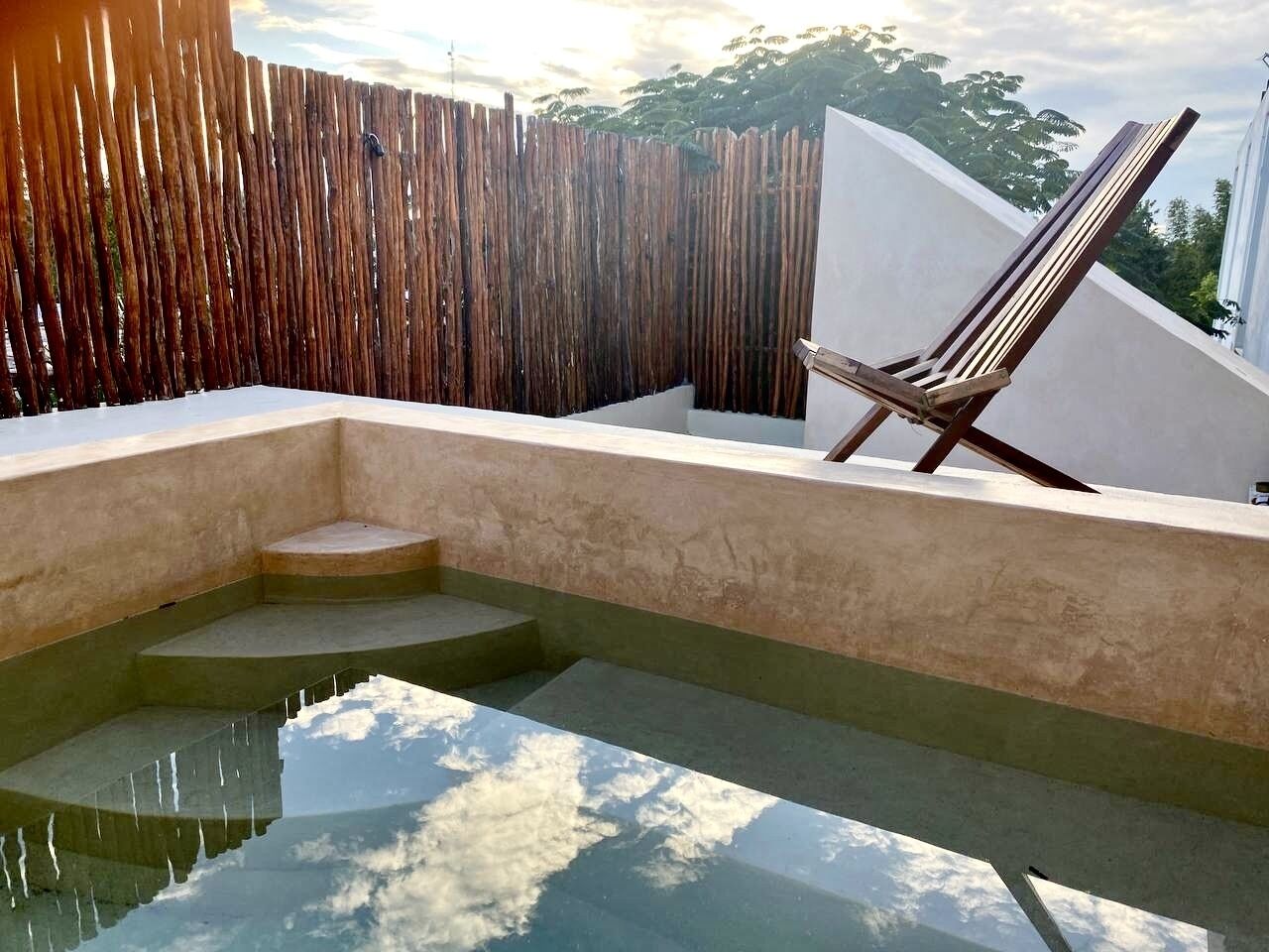 Pool på taget med en træstol og en bambushegn.