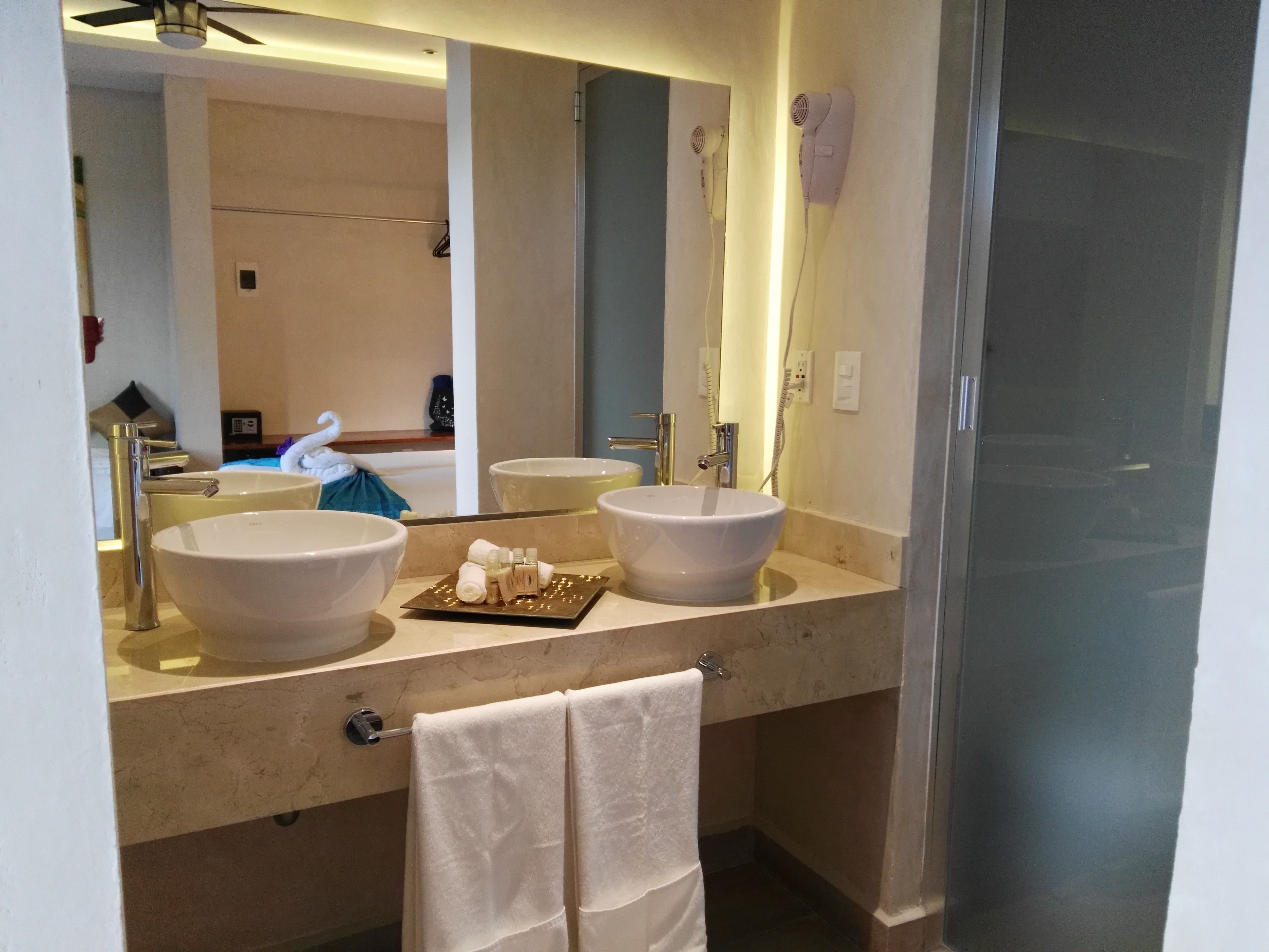 Un baño moderno con dos lavamanos grandes blancos, un espejo y un perchero para toallas.