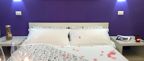 A bedroom with a bed, a bedside table, a vase, and a wall art piece.