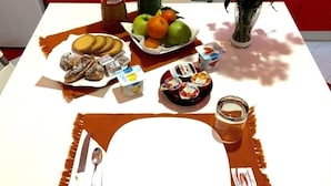 Una escena de desayuno con un plato, cubiertos y diferentes alimentos, como frutas, pastelería y salsas.