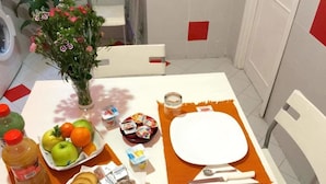 Una mesa de desayuno con frutas, pasteles y un florero.