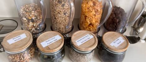 A collection of glass jars with wooden lids, each labeled with a different type of nut or seed.
