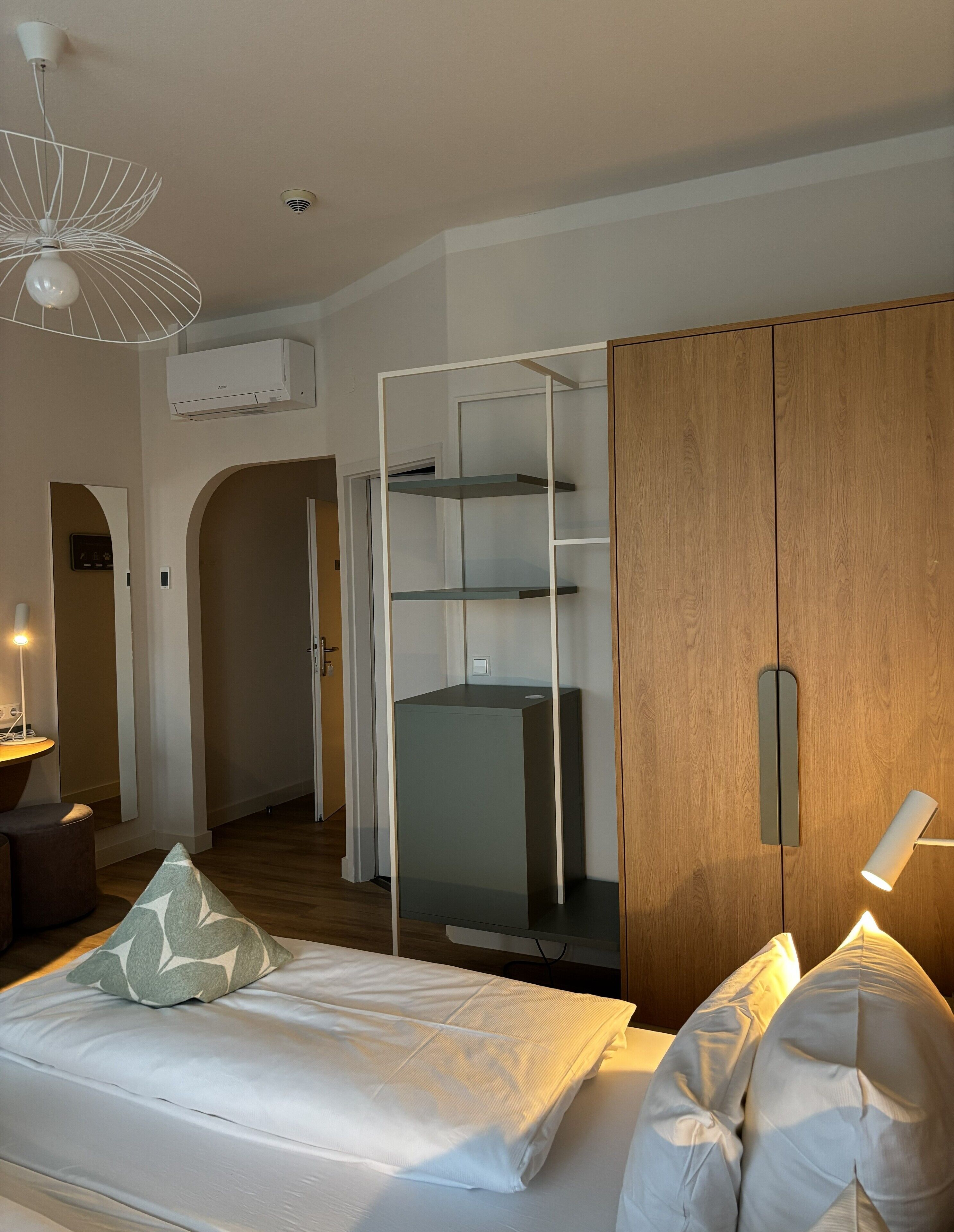 A modern bedroom with a bed, a wardrobe, and a built-in shelving unit.