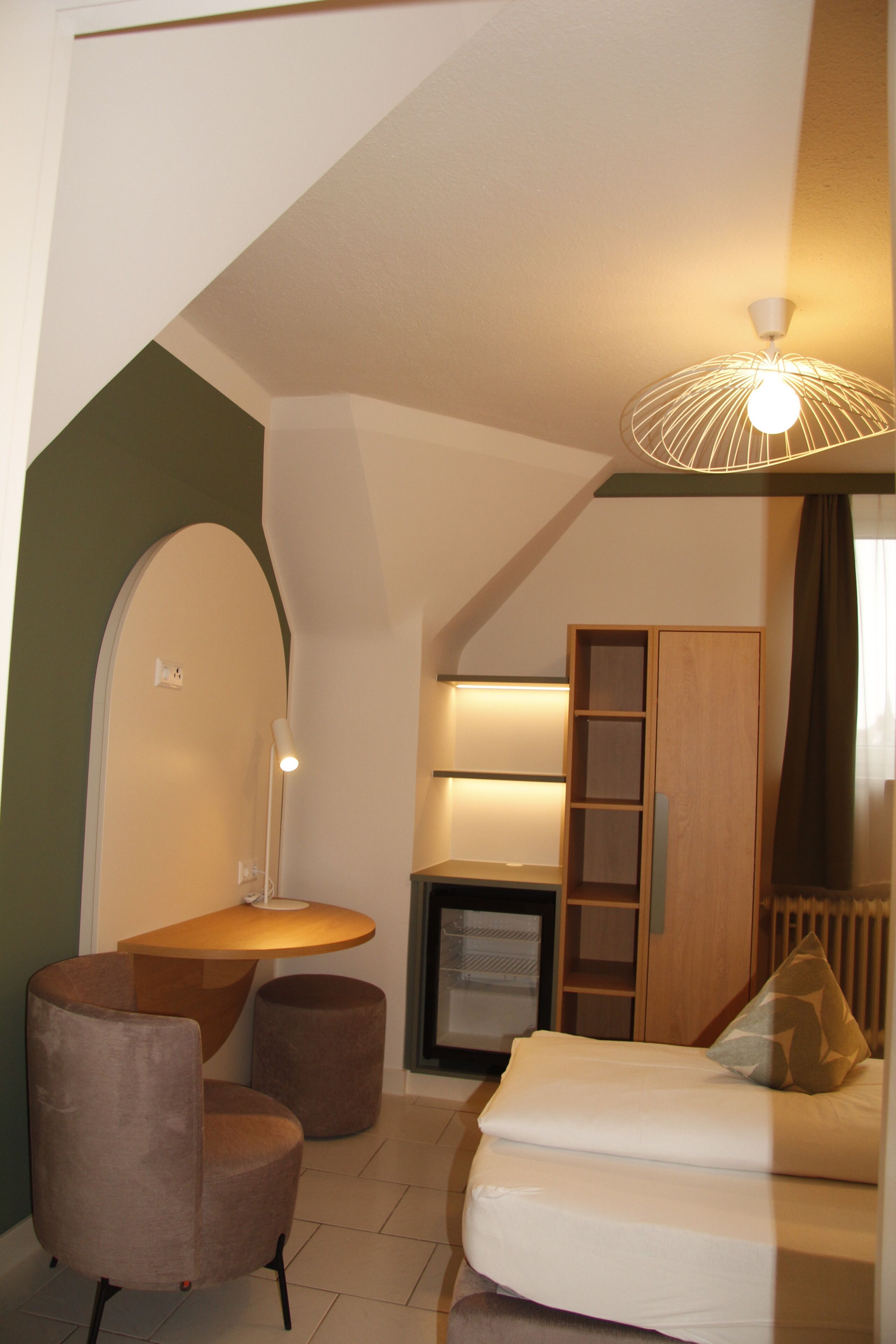 Un dormitorio moderno con cama, escritorio, silla y armario.