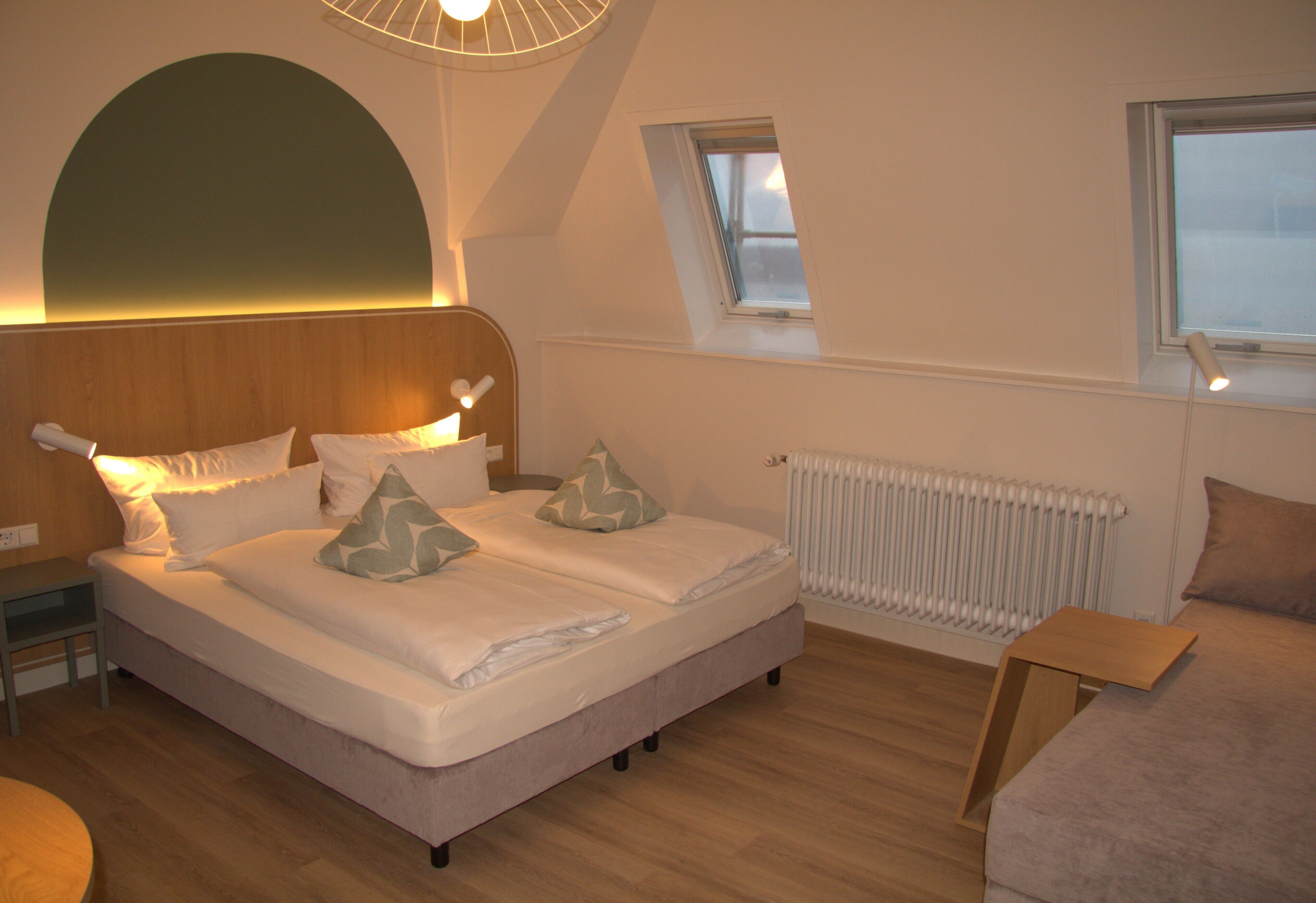 A bedroom with a bed, bedside tables, a radiator, and a window.