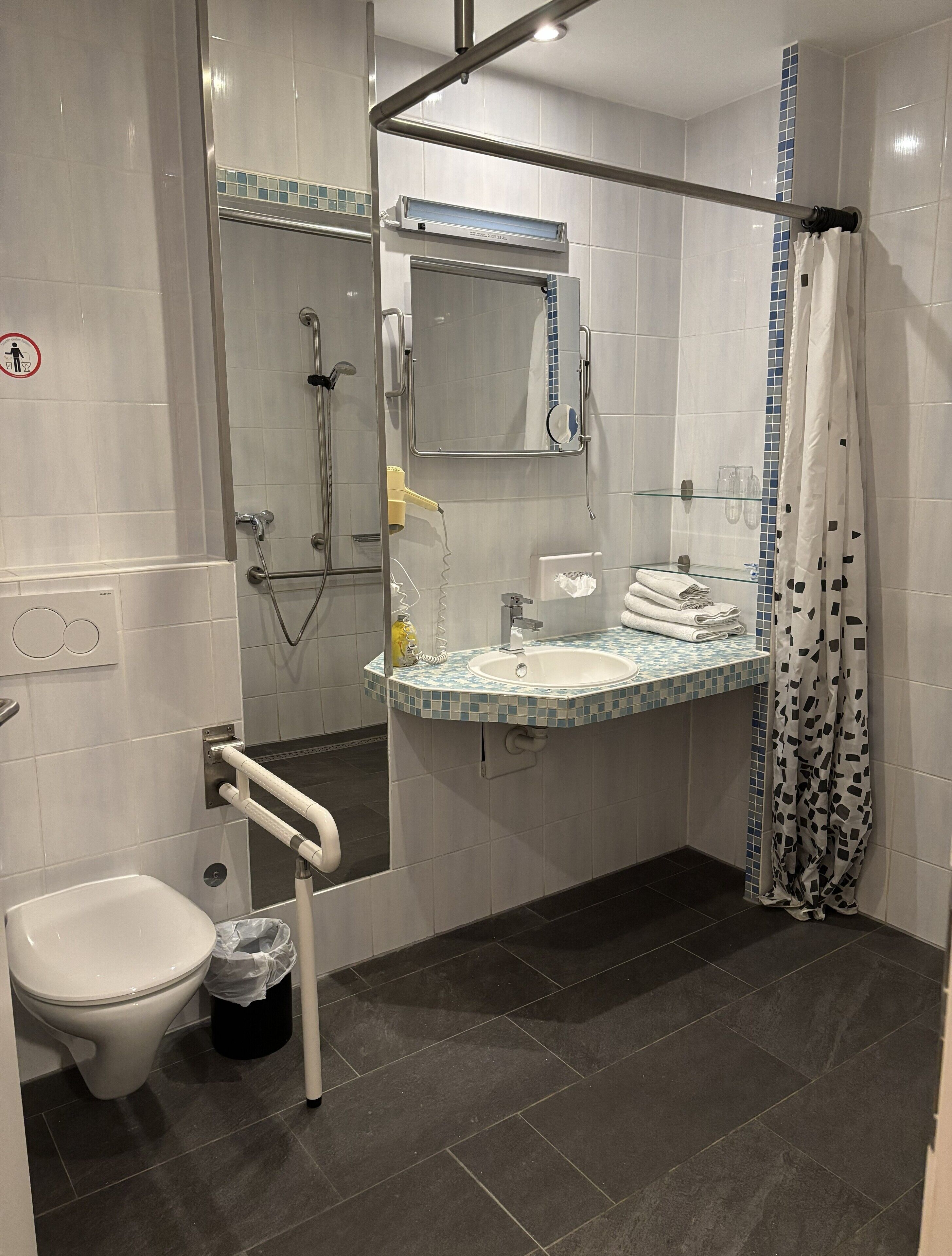 Ein modernes Badezimmer mit Toilette, Waschbecken und Duschbereich.