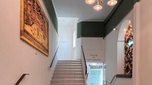 A staircase with patterned tiles, a reception area, and a chandelier. - Gästehaus Centro (Konstanz)