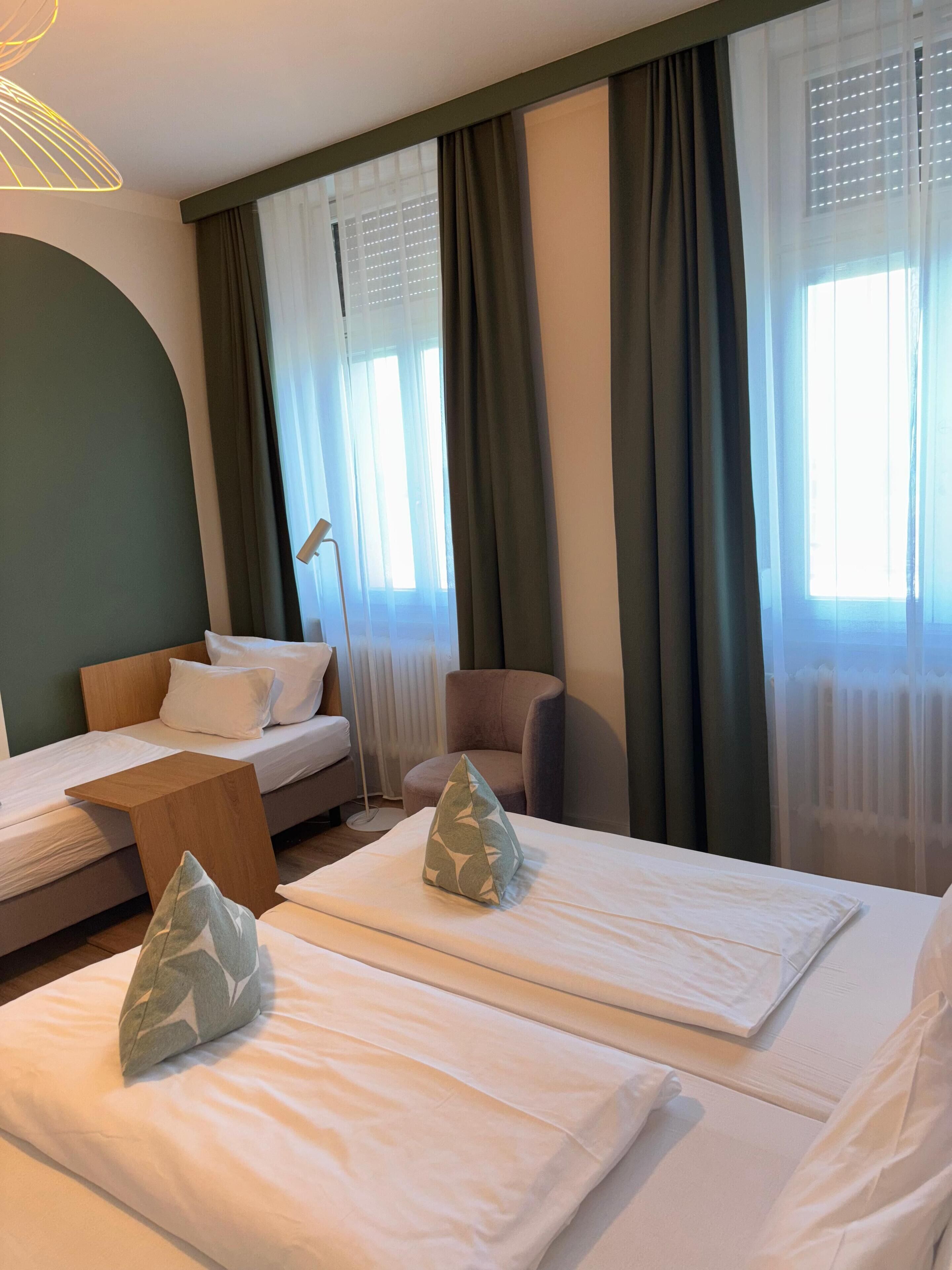 Una habitación de hotel con dos camas, una silla y una lámpara de pie.