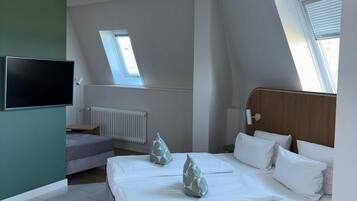 Ein modernes Schlafzimmer mit Bett, Schreibtisch, Stuhl, Fernseher und Deckenventilator.