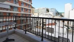 A balcony with a table and chairs, overlooking a cityscape with various buildings. - GoHouse Torre do Barao 506 (Rio de Janeiro)