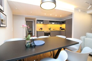 Ein moderner Essbereich mit einem dunklen Tisch, weißen Stühlen und einer Vase mit Blumen.