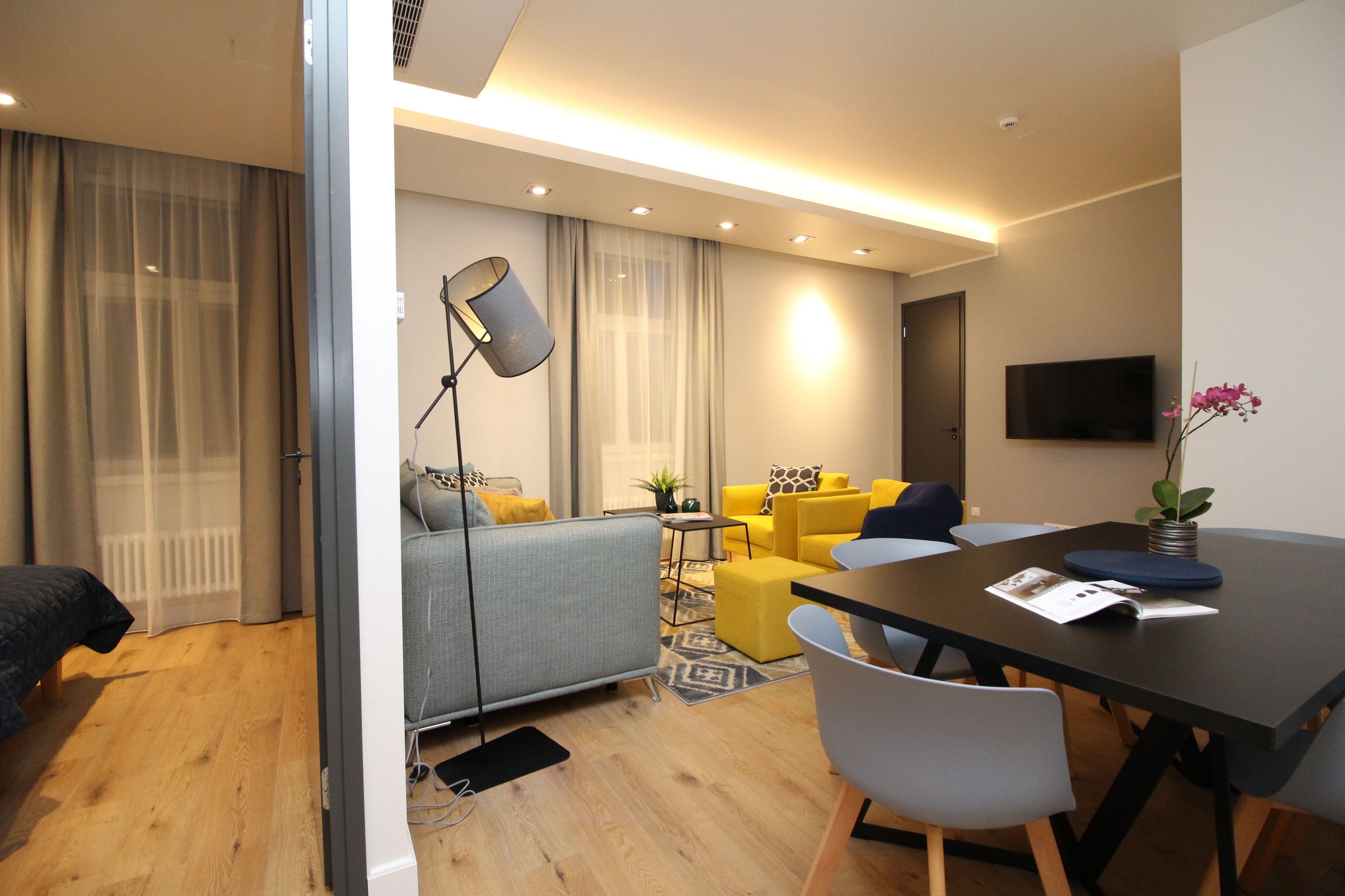 Une chambre d’hôtel moderne équipée d’un canapé, d’une table à manger et d’un téléviseur.